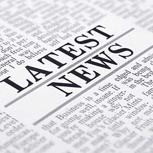 A newspaper close-up with the bold headline "LATEST NEWS" centered in black text. The background consists of densely packed, black text in various font sizes, typical of a newspaper layout.