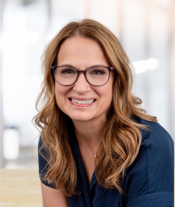 a middle aged brunette woman with glasses smiling