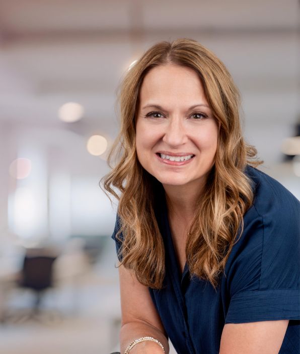 SYM Financial Advisors, an independent, commission-free fiduciary with 55+ years of serving clients: A smiling woman in a professional office setting, representing a commission-free fiduciary at SYM Financial Advisors.