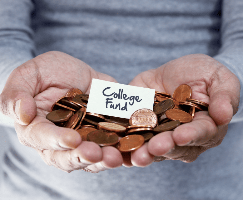 A pair of hands holding a pile of pennies with a small card on top that reads "College Fund." The background is out of focus, emphasizing the hands and the card.