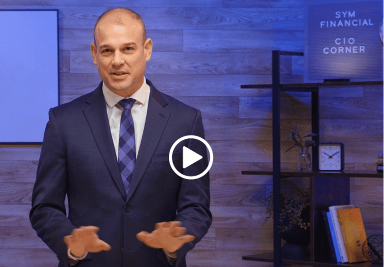 man in a blue suit with a blue plaid tie talking with his hands. video play button is on the image indicating video