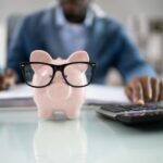 piggy bank with glasses on a desk by a computer