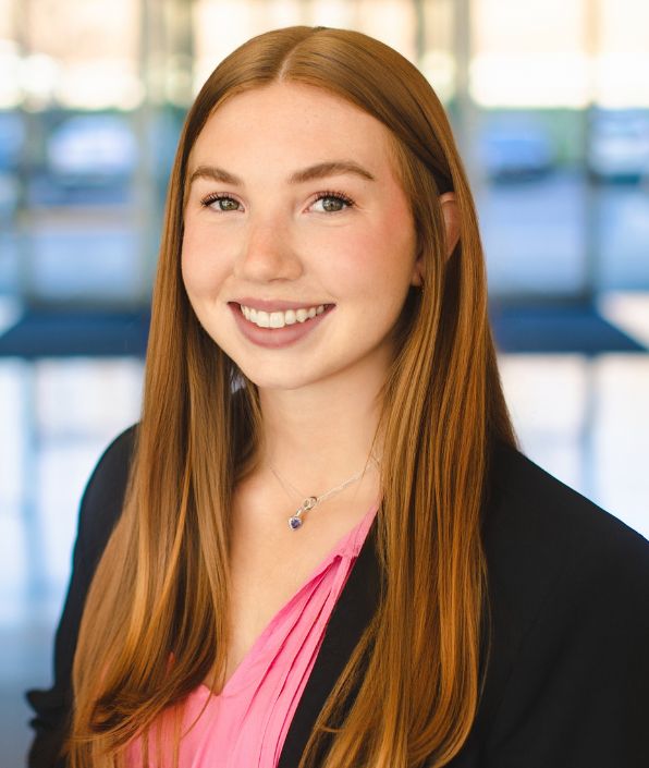 a young woman with red hair wearing a pink shirt under a blazer