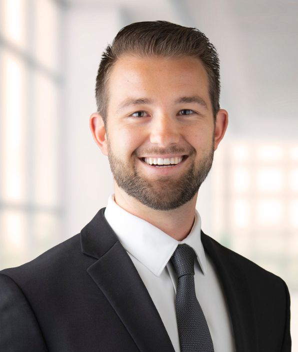 Young man with brown hair and a beard in a suit and tie
