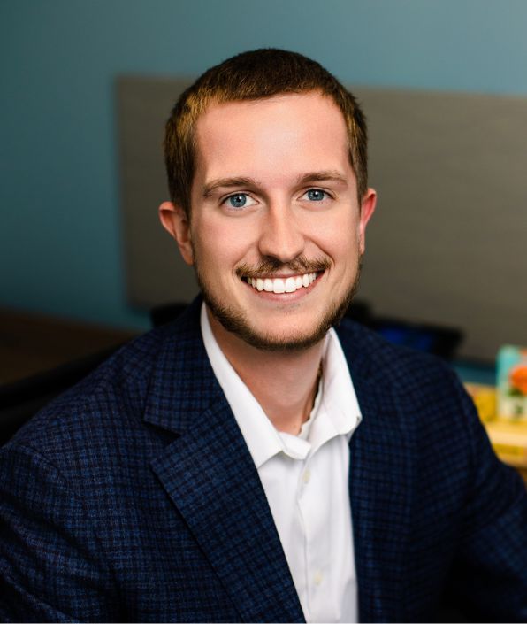 young man at his desk with moustache and beard smiling