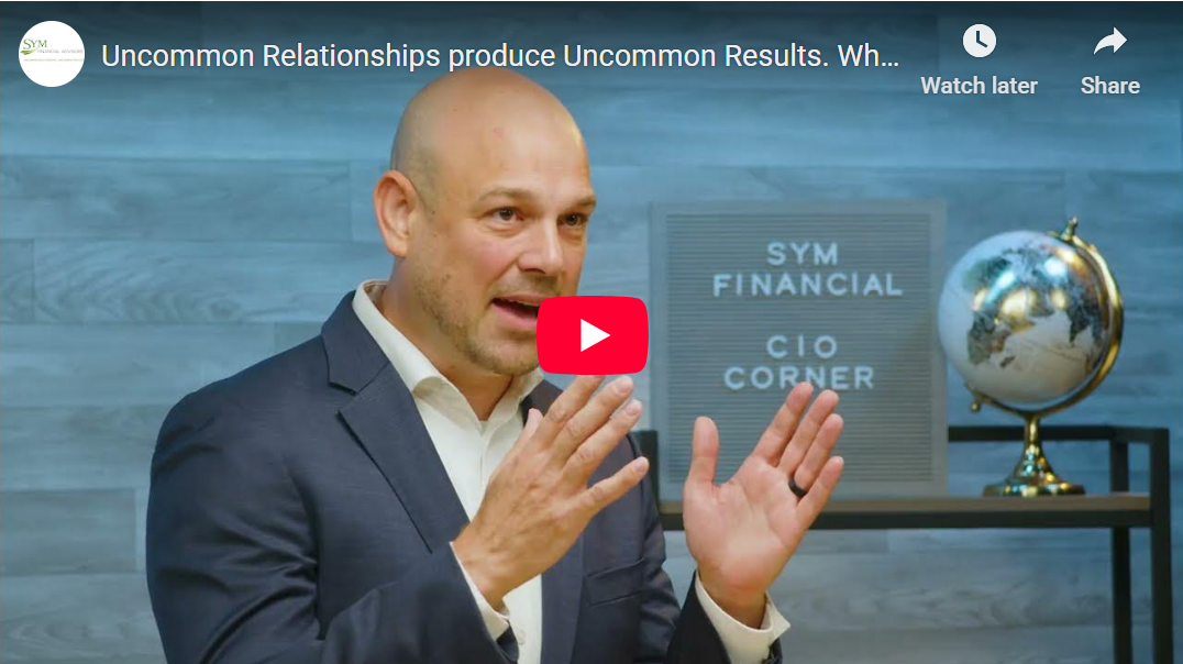 a video tile with a play icon on it. A middle aged man is talking in a blue suit jacket with his hands raised up.