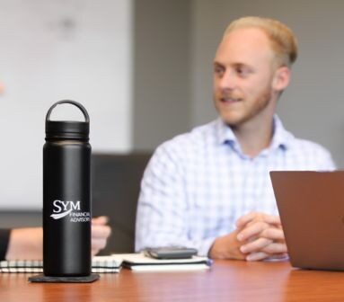 Middle aged man with blond beard named Ethan with SYM bottle and laptop at table