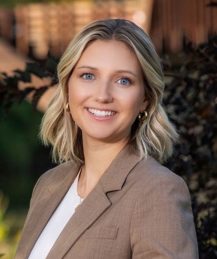 woman with blond hair and blue eyes in a tan blazer with white undershirt