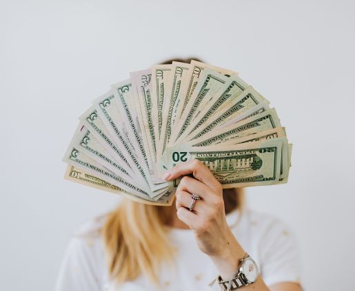 A woman holding up a fan or US $20 bills