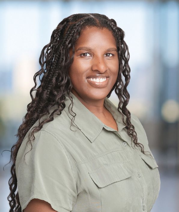 woman with long dark curly hair in a light khaki blouse