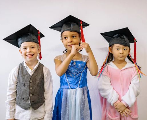 Three children wearing graduation caps stand together, representing the future goal of using 529 plans for qualified education expenses, a strategy supported by SYM Financial Advisors, an independent, commission-free fiduciary with 55+ years of serving clients.